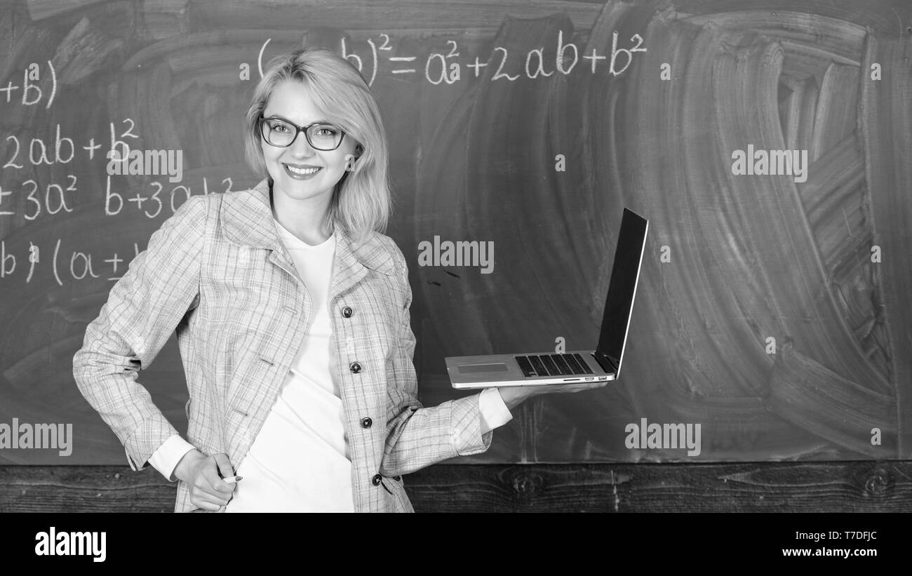 Enseignante portent des lunettes est titulaire d'ordinateur portable Internet surf. Dame intelligente smart éducateur avec ordinateur portable moderne tableau internet surf arrière-plan. Les technologies numériques concept. L'apprendre de manière simple. Banque D'Images