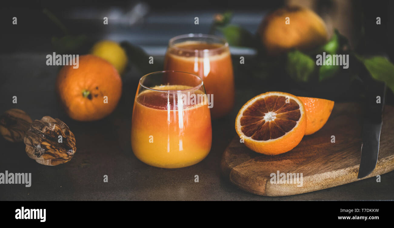 Verres de jus d'orange fraîchement pressé ou sang smoothie sur comptoir de cuisine en béton, close-up. Mode de vie sain, végétarien, végétalien, régime alimentaire, l'alcaline Banque D'Images