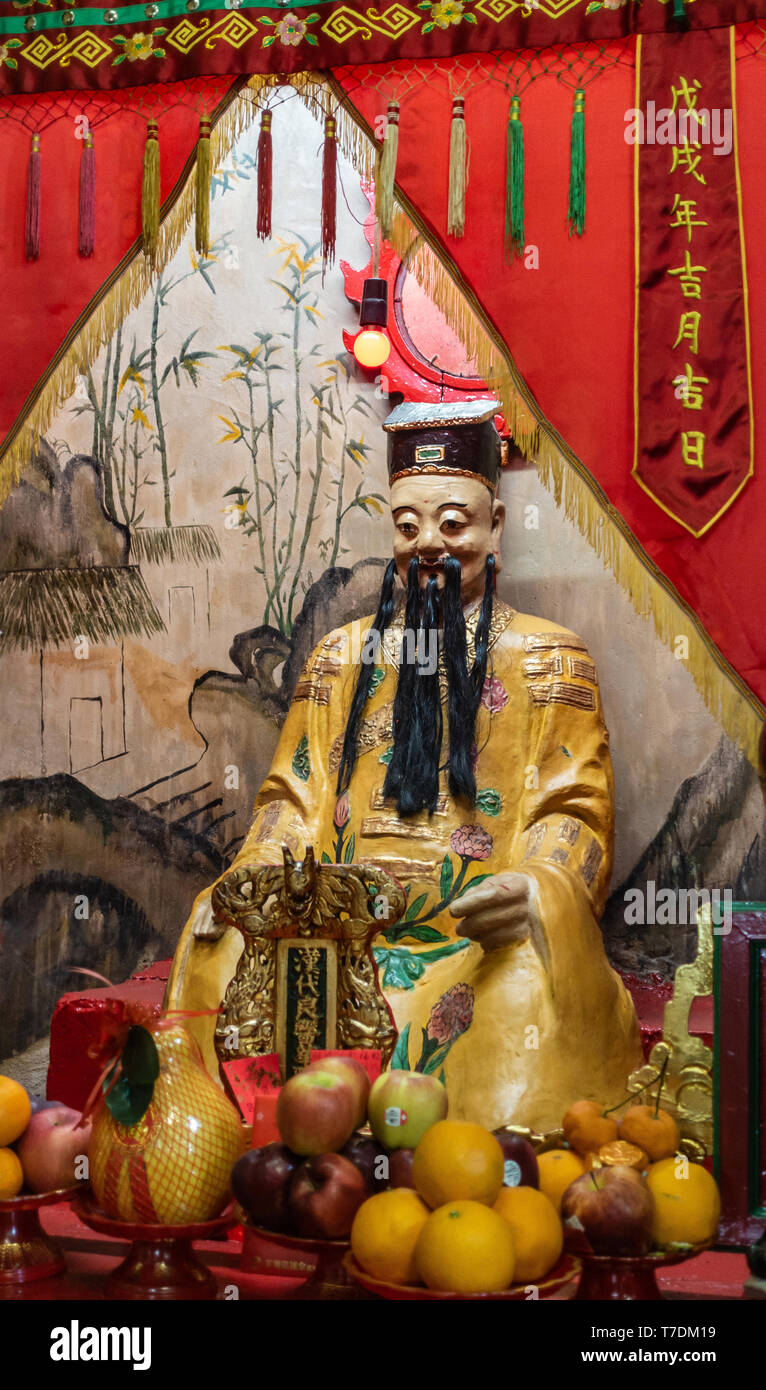 Hong Kong, Chine - 7 mars, 2019 : Tai O village de pêcheurs. Gros plan du dieu de la médecine à Kwan Tai temple taoïste. Robe jaune s'use et se place derrière whit Banque D'Images