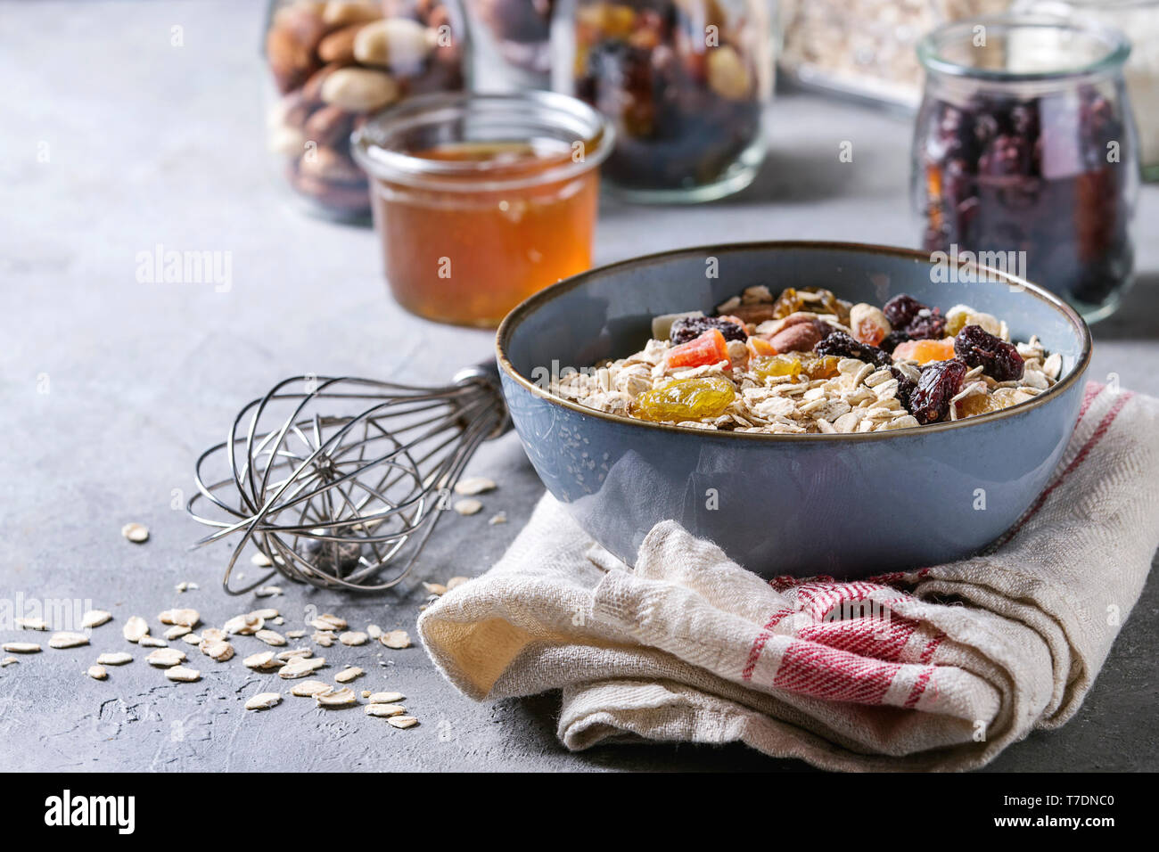 Variété de fruits secs, noix, miel et flocons d'avoine dans un bol et différents pots de verre pour la cuisson des petit-déjeuner sain ou muesli muesli énergie b Banque D'Images