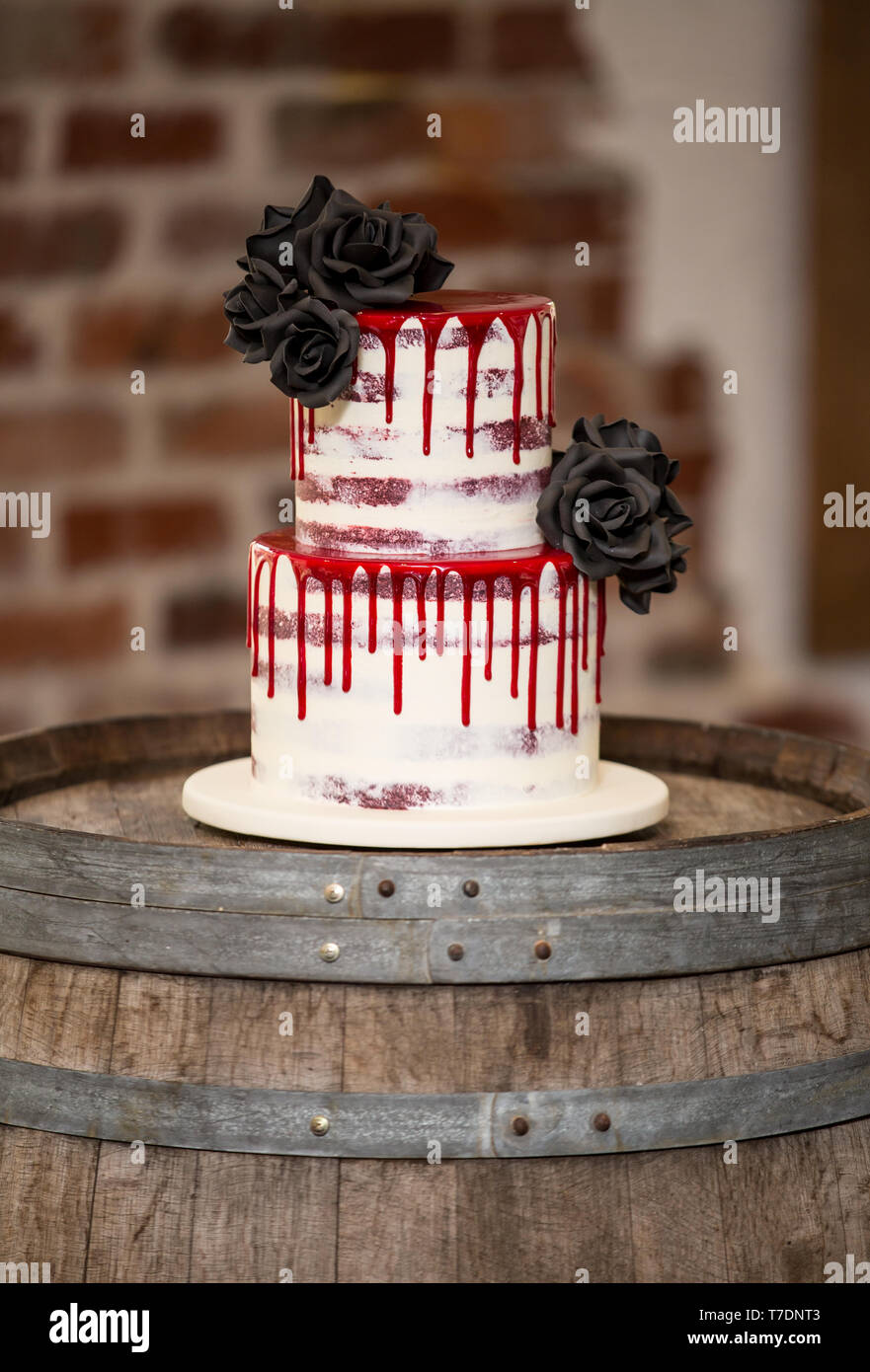 Gâteau de mariage moderne noir avec fleurs et glaçage rouge Banque D'Images