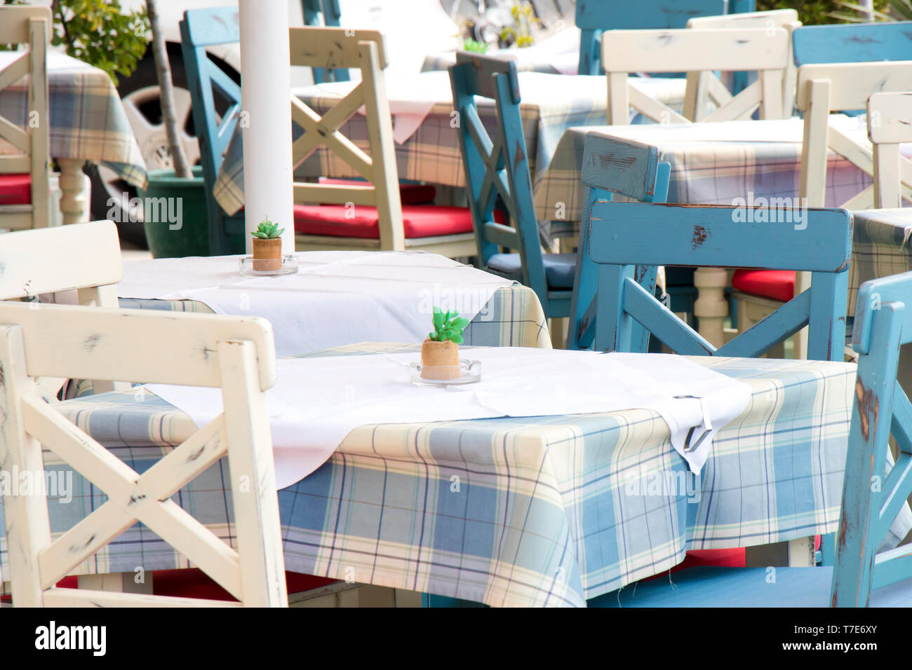 Des tables et des chaises dans un restaurant méditerranéen traditionnel typique sur la terrasse à la lumière bleu et blanc avec nappe à carreaux, détail Banque D'Images