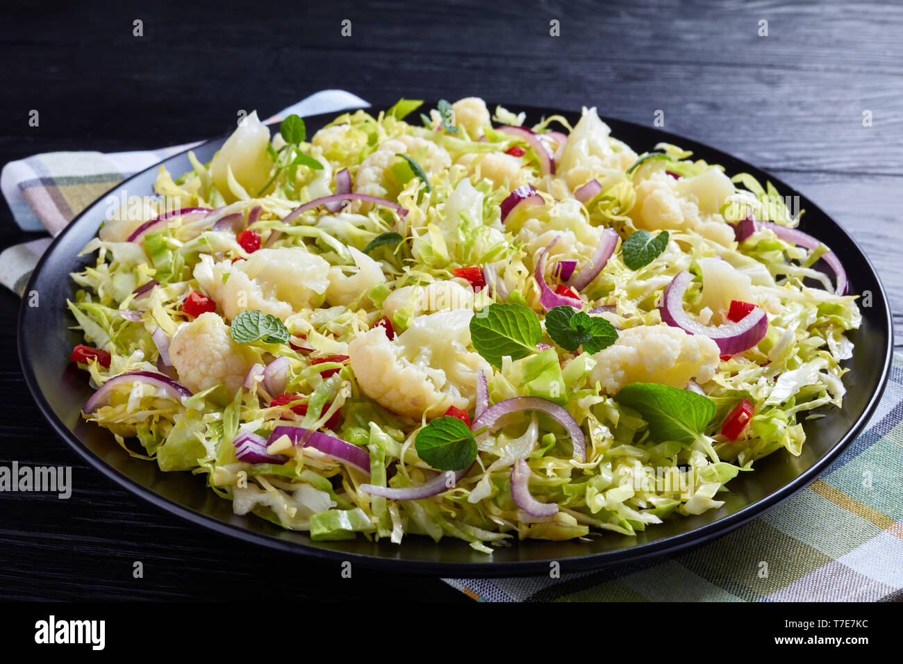 Salade de chou-fleur avec chou râpé, le poivron, l'oignon rouge et de menthe fraîche sur une plaque noire sur une table en bois, vue horizontale à partir de ci-dessus, fermez-u Banque D'Images