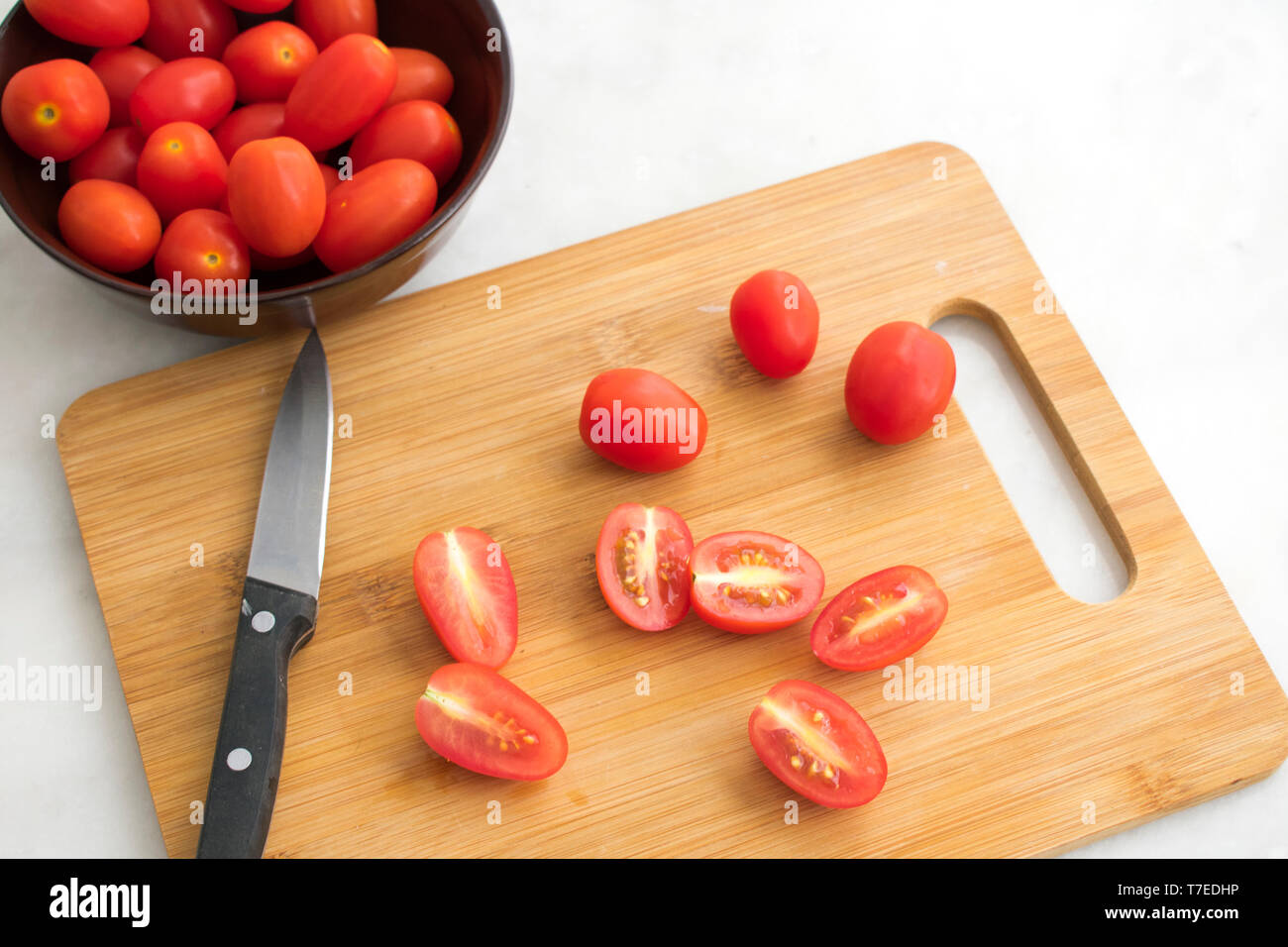 Découper les tomates en vigne sur une planche à découper Banque D'Images