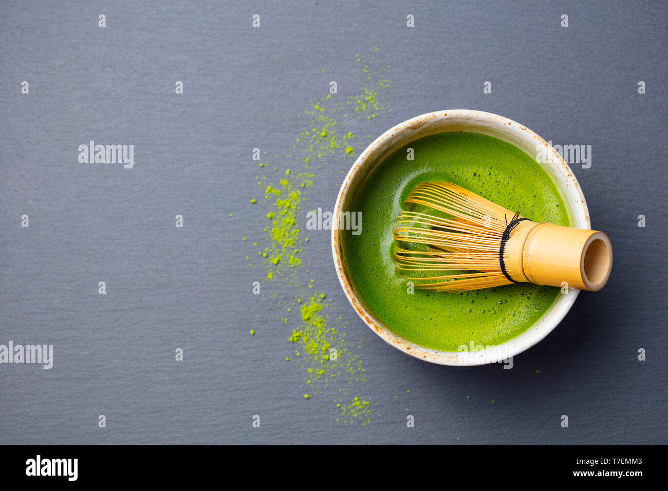 Thé vert matcha processus de cuisson dans un bol avec un fouet en bambou. Arrière-plan en ardoise noire. Vue d'en haut. Copier l'espace. Banque D'Images