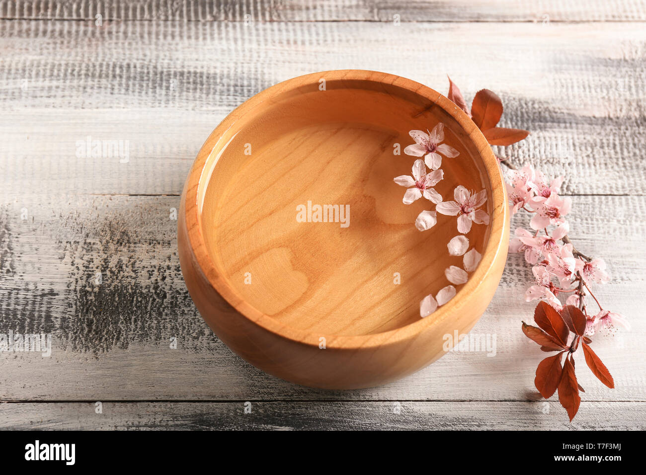 Bol avec de l'eau et de fleurs sur table en bois Banque D'Images