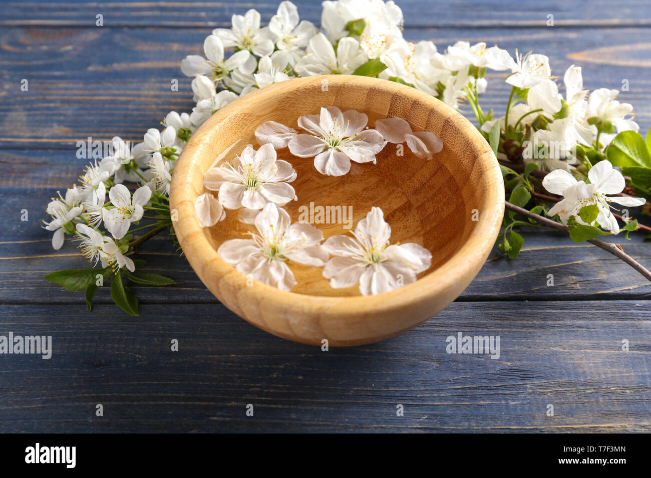 Bol avec de l'eau et de fleurs sur table en bois Banque D'Images