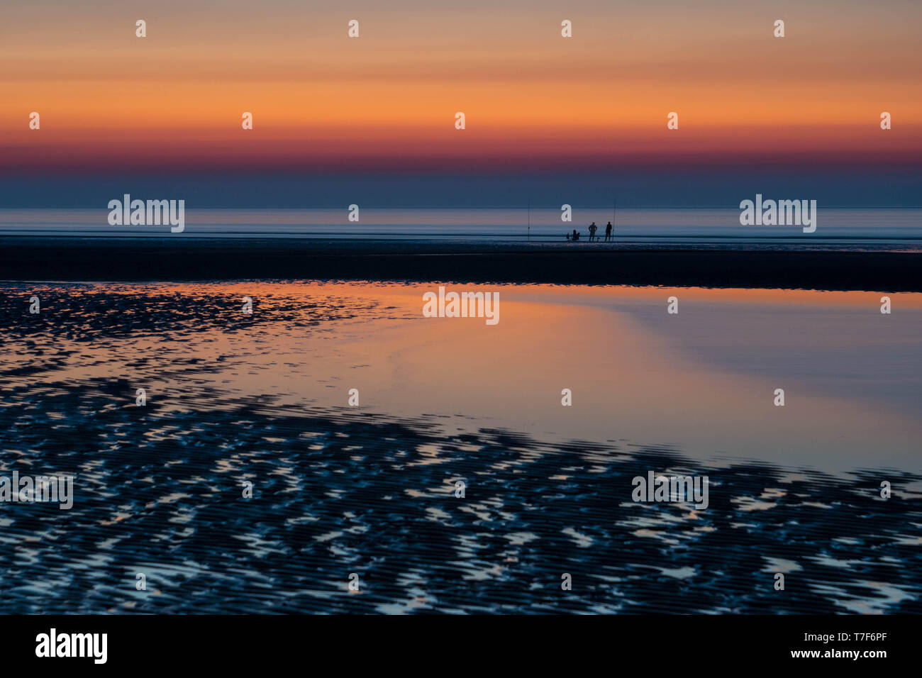 Silhouettes de pêcheurs pendant le coucher du soleil spectaculaire sur un banc Banque D'Images