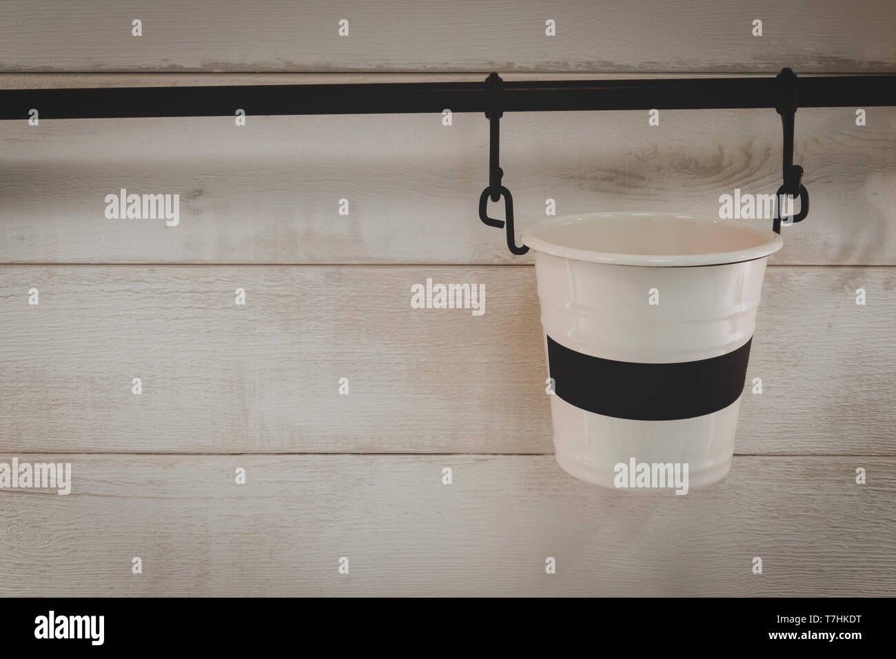 Petit seau métal blanc vide ou pot accroché au bar avec un mur dans la chambre. Décoration maison objet et concept de l'intérieur. Banque D'Images