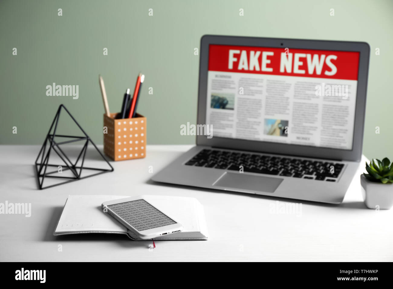 Ordinateur portable, téléphone et ordinateur portable avec des mots FAUX NEWS sur écran dans la salle Banque D'Images