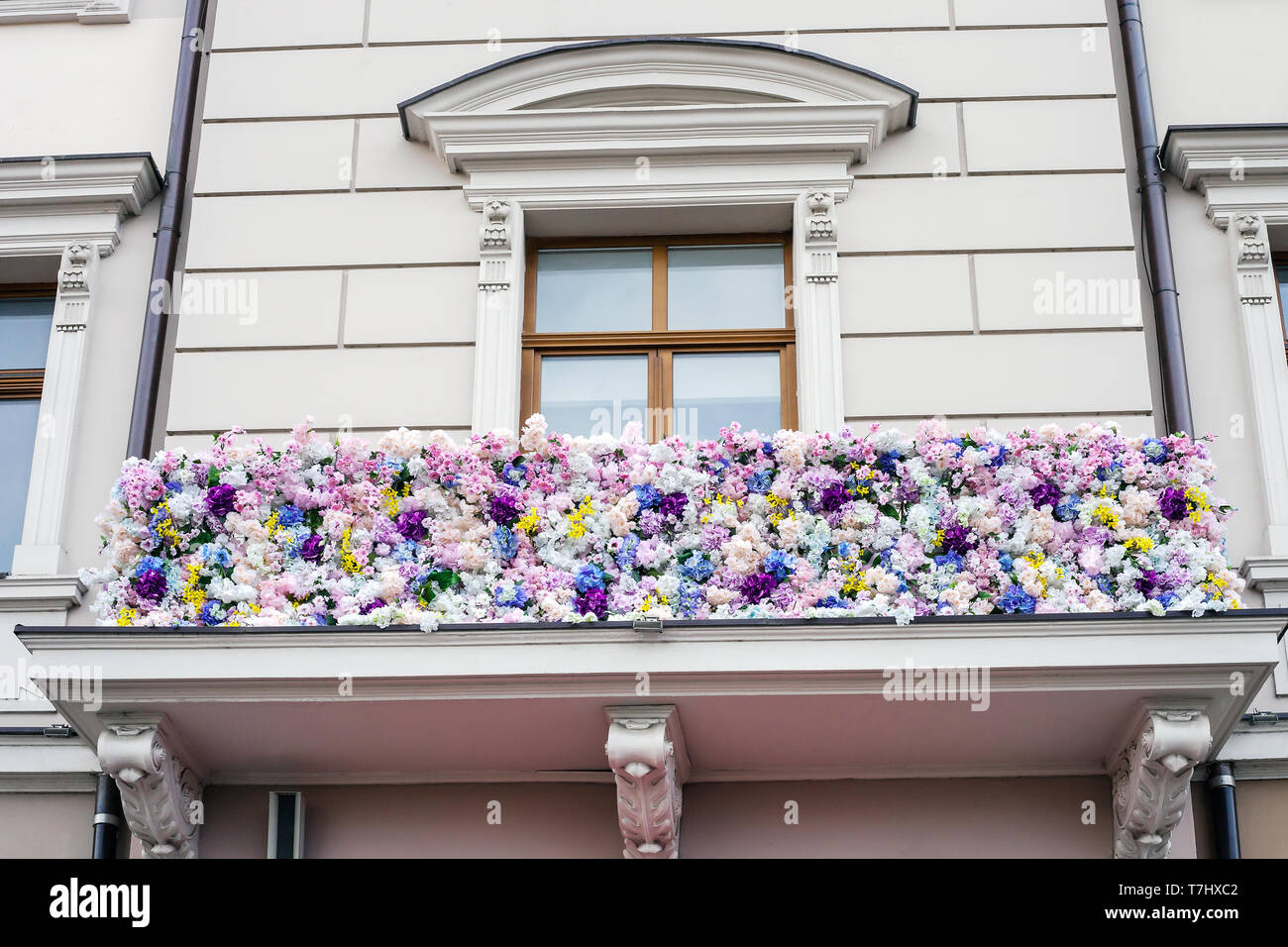 Balcon de chambre décorée avec diverses fleurs artificielles. Partie de la  façade de l'immeuble avec fenêtre et décor floral, romantique extérieur  style design Photo Stock - Alamy