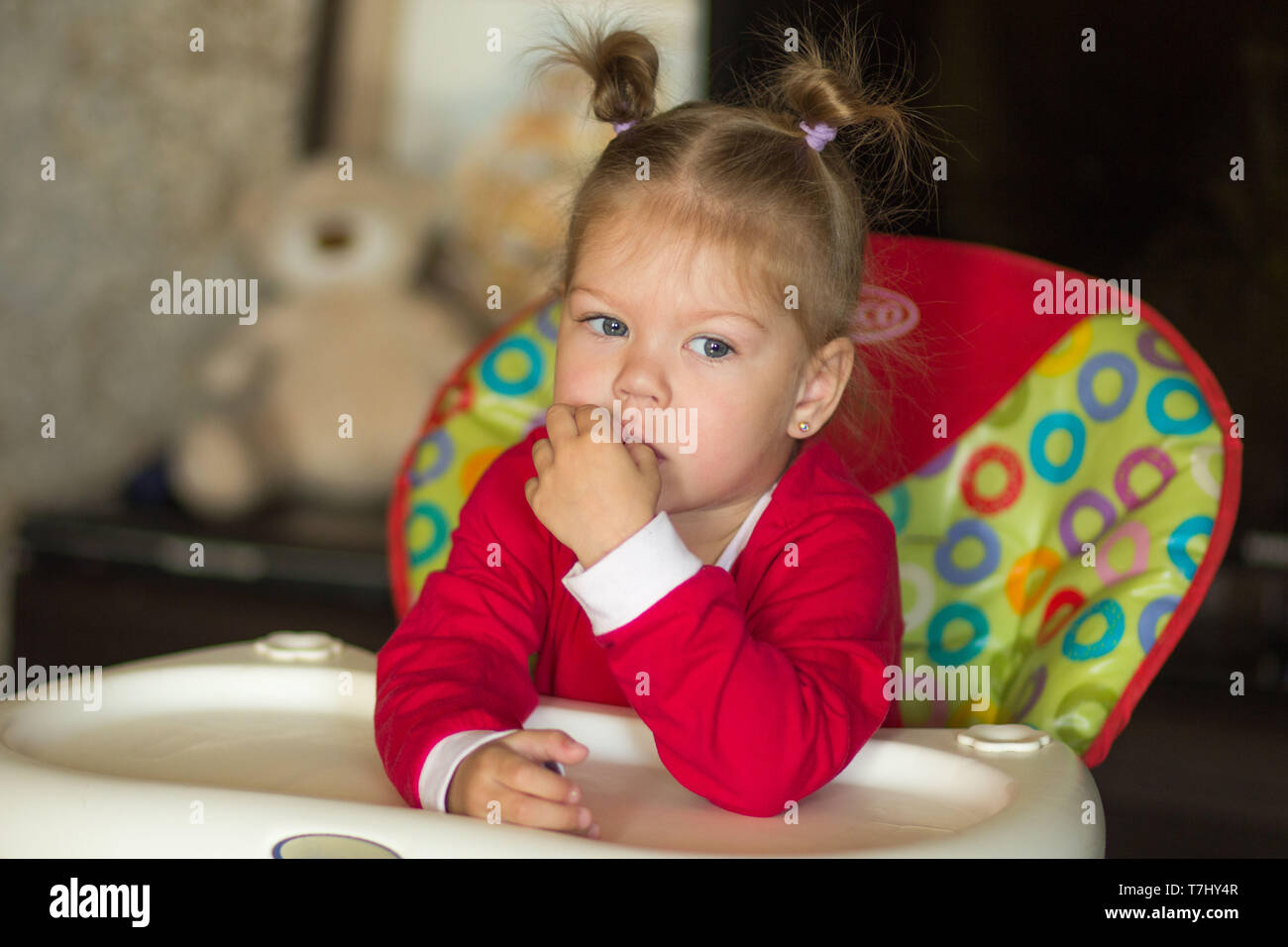 Portrait de petite fille avec pensive regard regarder de côté, assis dans la chaire de l'alimentation Banque D'Images