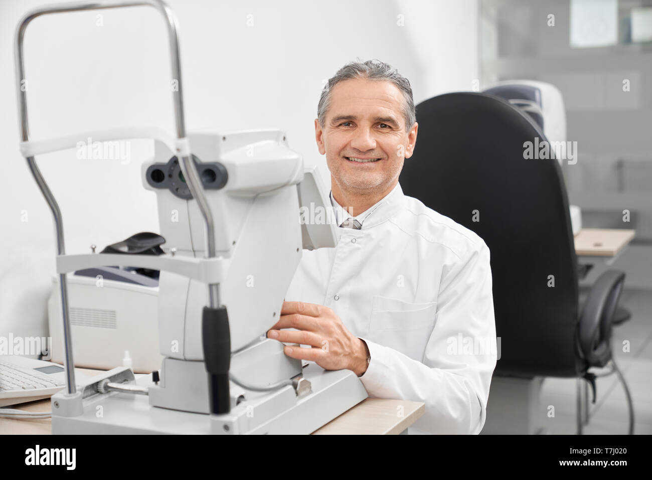 Médecin Optométriste portant en blanc manteau médical travaillant sur l'ophtalmologie spécial dans l'équipement de bureau de l'opticien. Traitement et correction de la vision moderne de la machine avec la lampe à fente. Banque D'Images