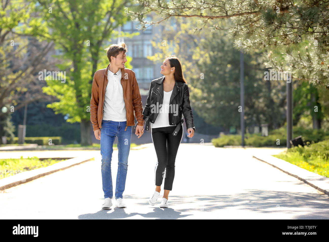 Happy young couple walking together in city park Banque D'Images