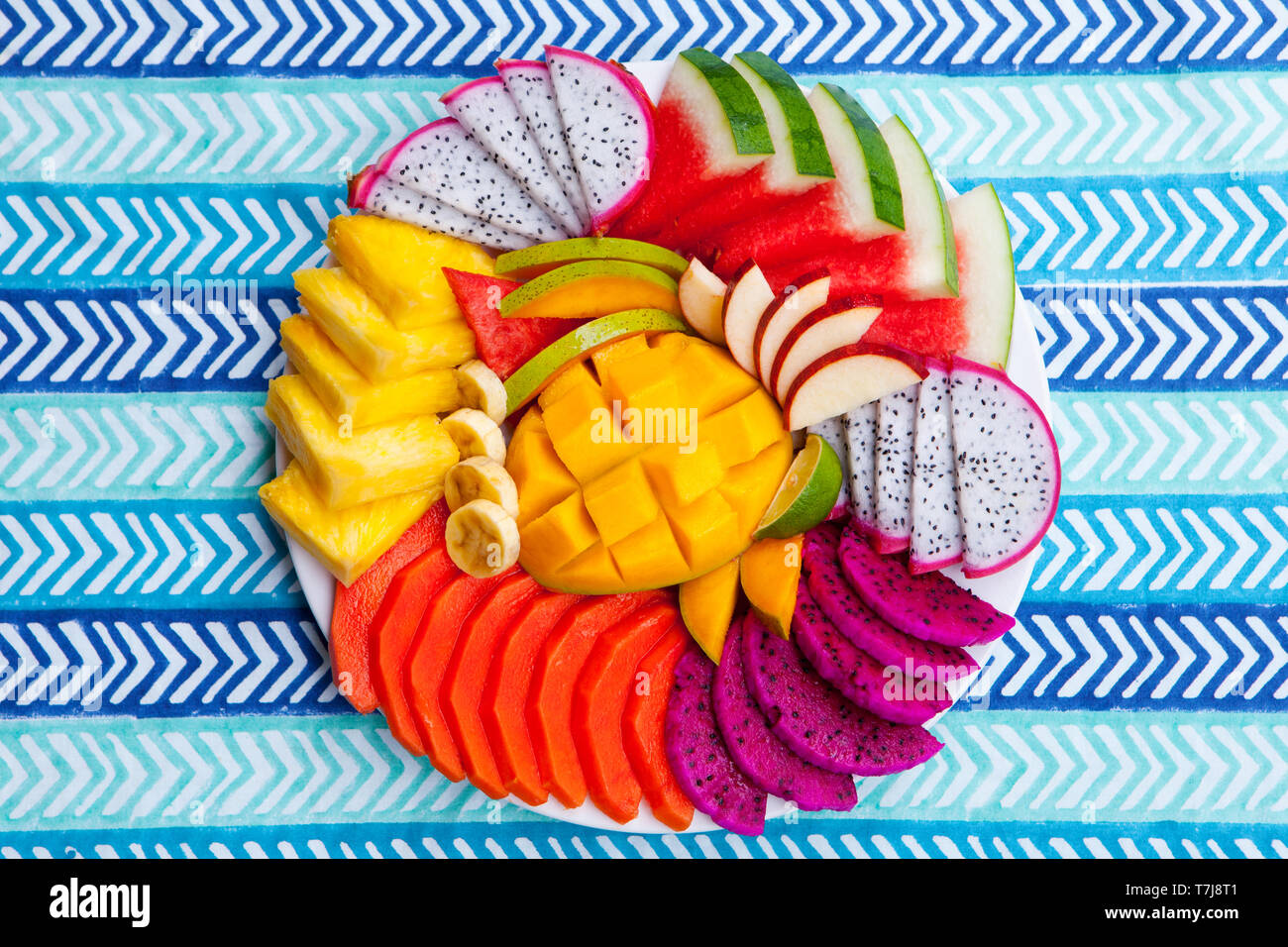 Assortiment de fruits tropicaux sur une plaque blanche, bleu fond textile coloré. Vue d'en haut. Copier l'espace. Banque D'Images