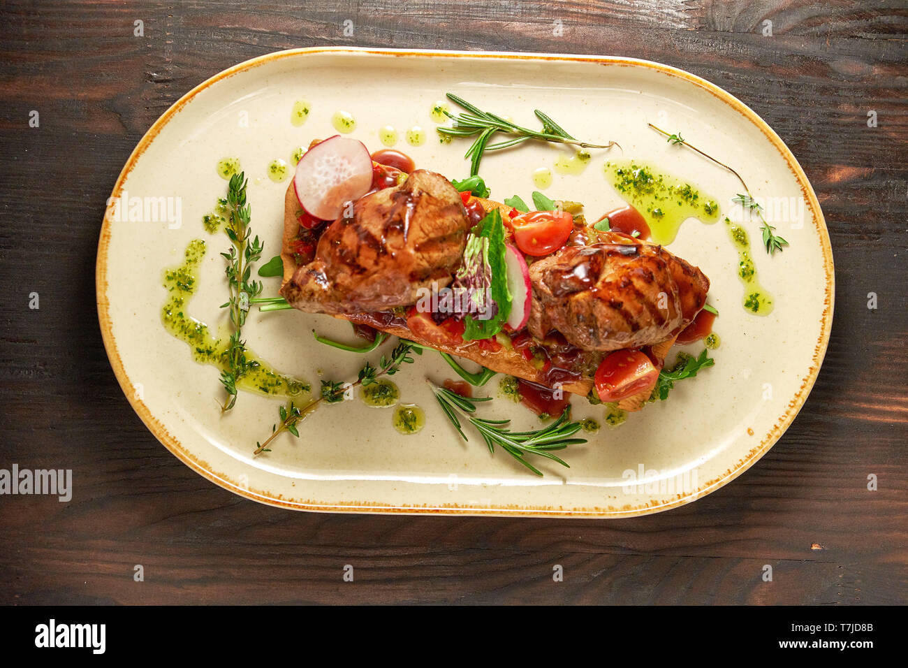 La viande grillée sur le pain pita au romarin et légumes : radis, tomate, sur une plaque ovale lumineux. Fond en bois sombre. Restaurant menu Banque D'Images