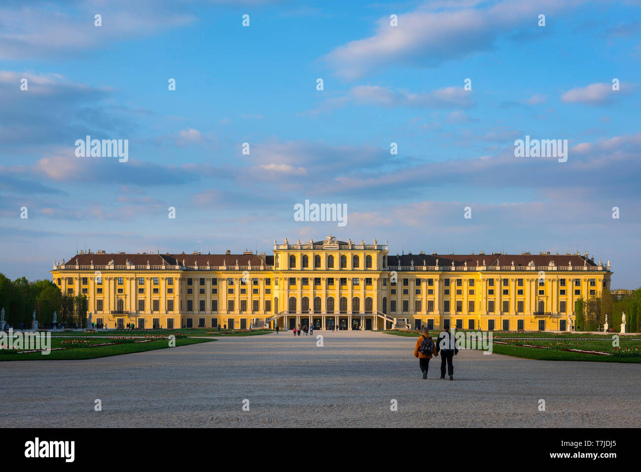 Palais de Vienne, vue au coucher du soleil d'un couple d'âge moyen marchant vers le côté sud du château historique de Schönbrunn à Vienne, Autriche. Banque D'Images