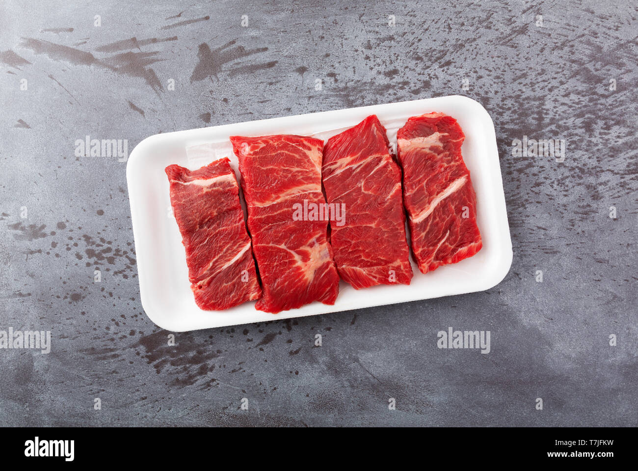 Vue de dessus de plusieurs morceaux de viande bovine désossée côtes courtes chuck steaks grillés sur un plateau de mousse sur un comptoir gris éclairés par la lumière naturelle. Banque D'Images