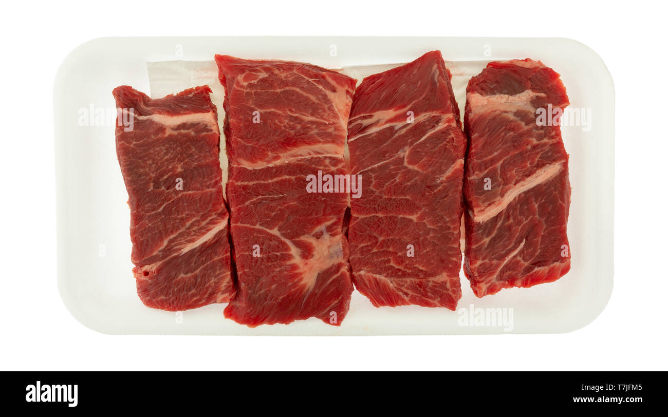 Vue de dessus de plusieurs morceaux de viande bovine désossée côtes courtes chuck steaks grillés sur un bac à mousse isolé sur un fond blanc. Banque D'Images