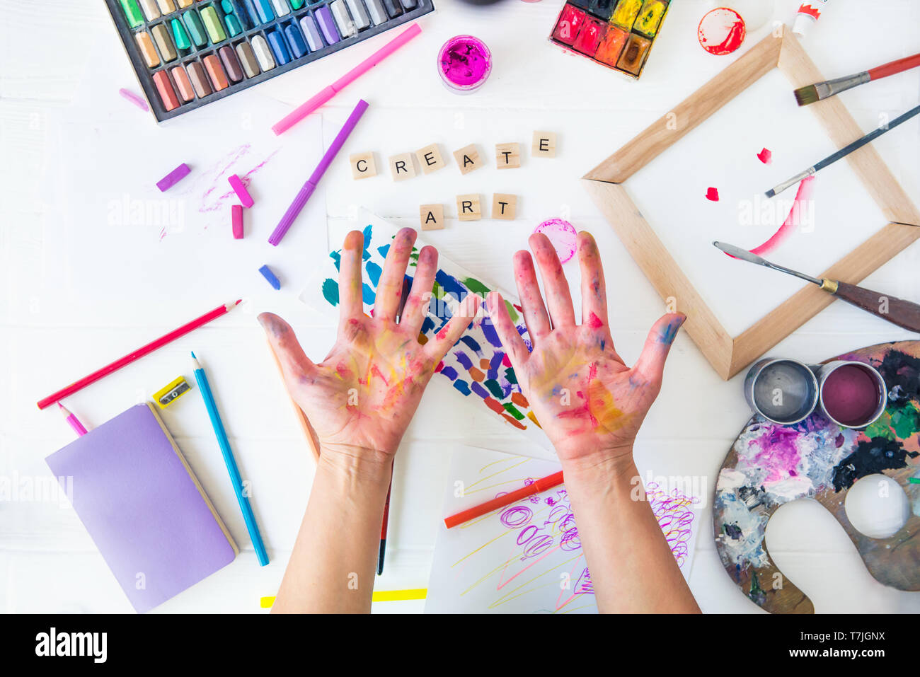 Vue supérieure ouverte femelle peint main sur créer de l'art mots lettrage en paintiing beaucoup de matériaux colorés sur fond blanc. Atelier d'art, dessin Banque D'Images