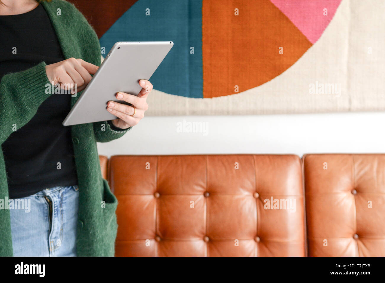 Jeune femme à la mode à l'aide de tablette à la maison avec intérieur à la mode Banque D'Images