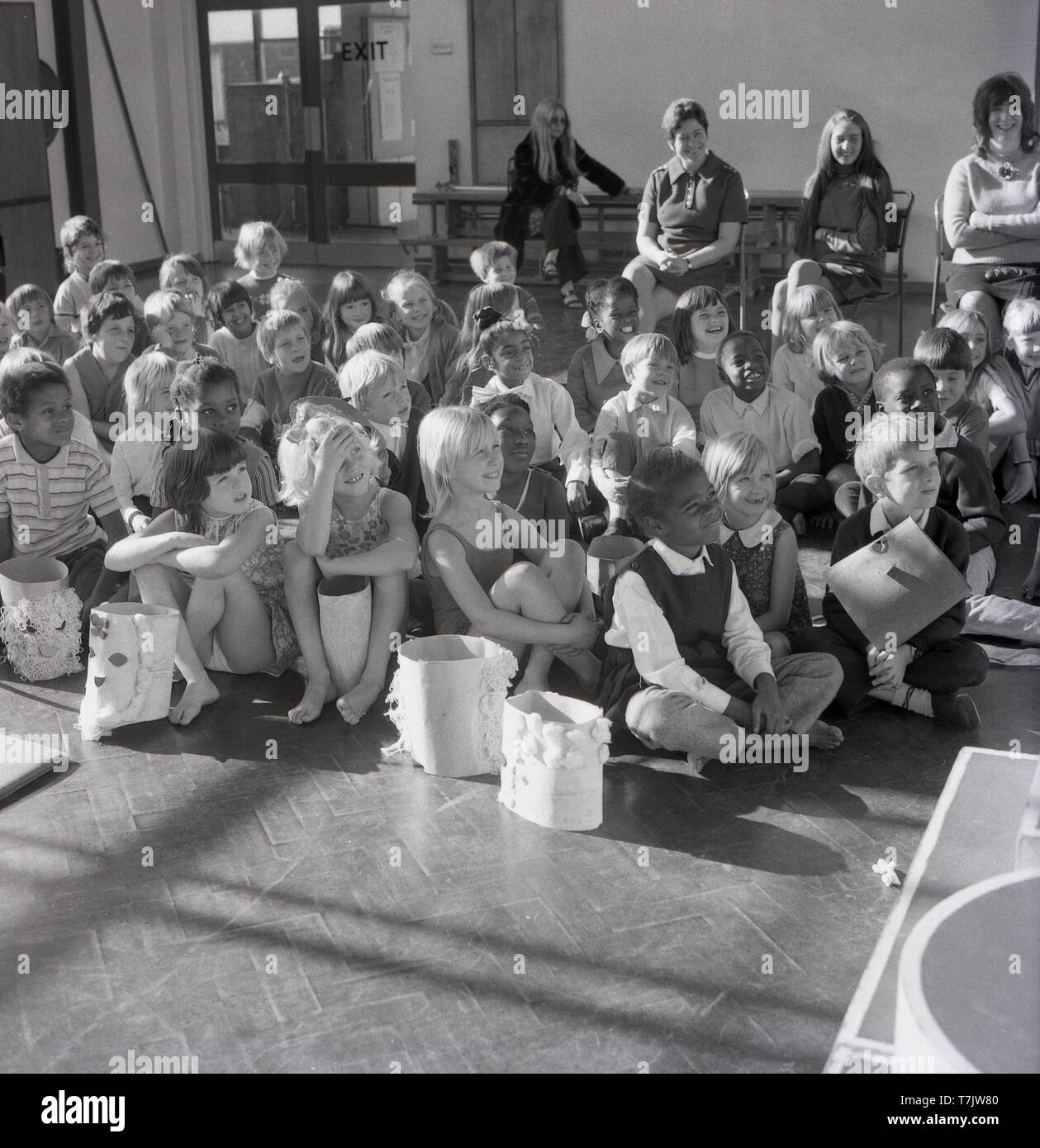 Années 1960, historiques, les jeunes enfants de l'école dans la salle d'école leur main pour poser une question, England, UK. Banque D'Images