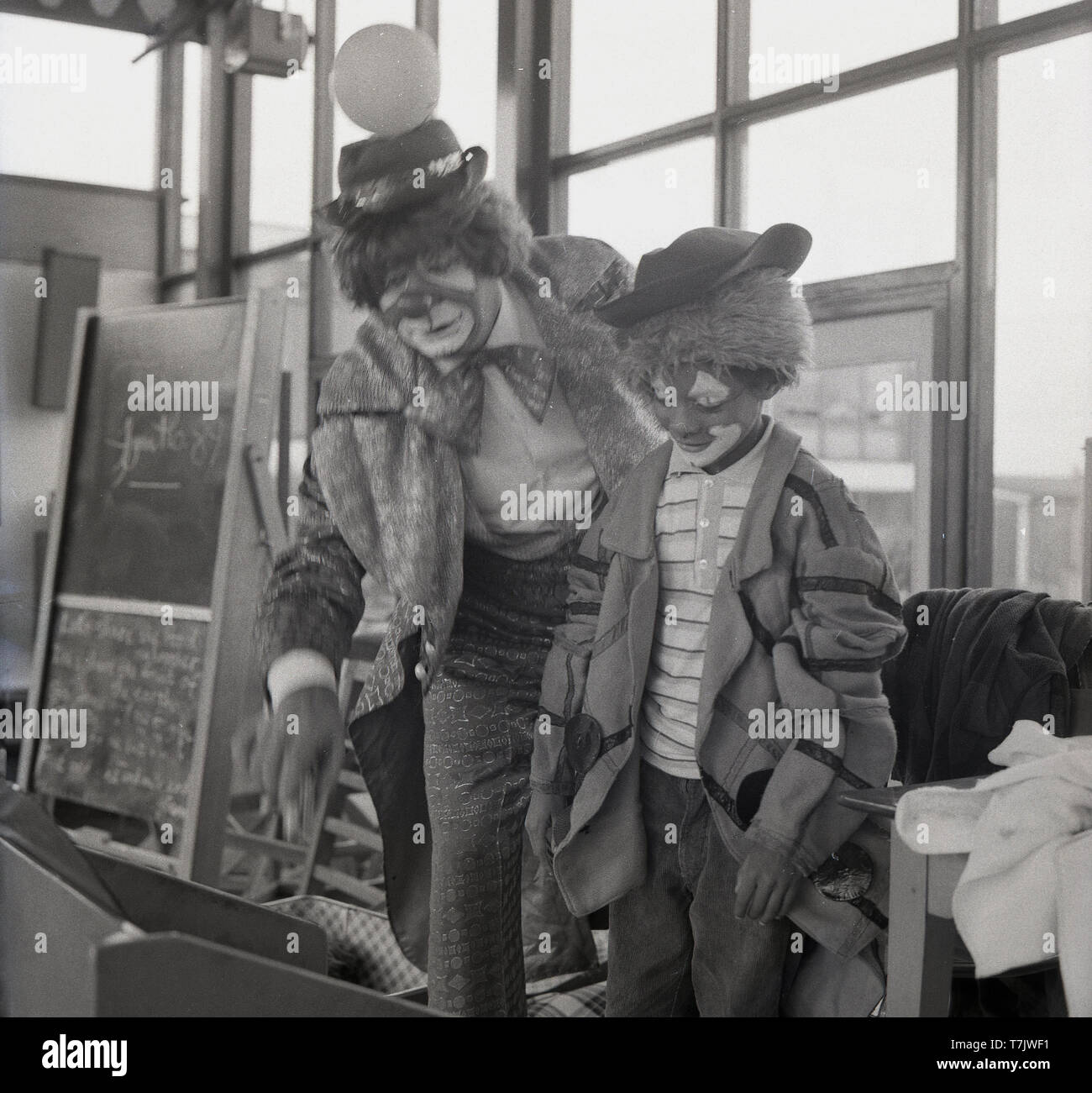 Années 1960, historique, un clown de cirque avec un jeune écolier a également habillé et avec ses visages peints comme un clown, England, UK. Banque D'Images
