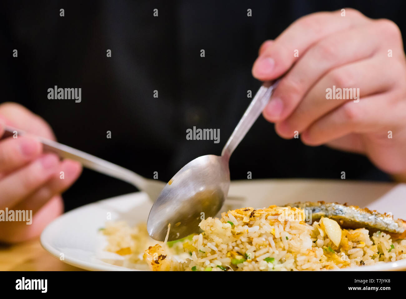 Poêlée de saumon en tranches avec du riz frit.man mains utiliser fourchette et cuillère pour fusion food.tranches de saumon avec du riz sur plaque blanche en restaurant ou un café.man stit Banque D'Images