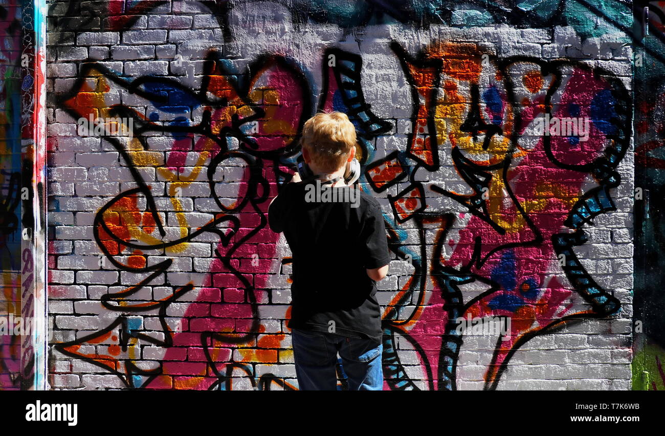 La photo d'un jeune garçon sur tippy-orteils de peindre sur un mur légal à Cambridge, MA (le 17 avril 2019) Banque D'Images