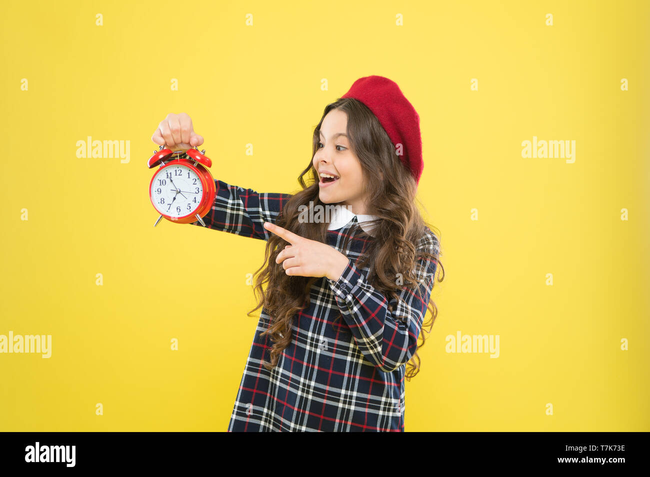 Fille avec réveil. Mettre en place un réveil. Petite fille enfant tenir horloge rouge. Il est temps. Toujours à l'heure. Il n'est jamais trop tard. Définir votre propre rythme de vie. Happy hours concept. L'annexe et du moment. Banque D'Images