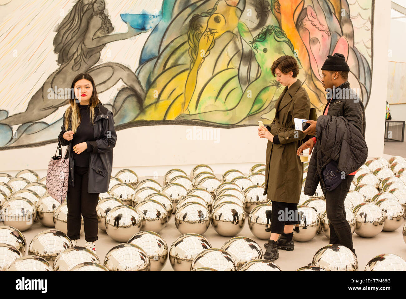 New York, NY - 3 mai 2019. Les spectateurs se promener dans l'Kusame Yayoi Narcissus 'jardin' plein de sphères en acier inoxydable, en face de Chris Blifi's oil 'à prendre et à donner' dans la Victoria Miro Gallery à la Frieze Art Fair de New York City's Island Randalls. Banque D'Images