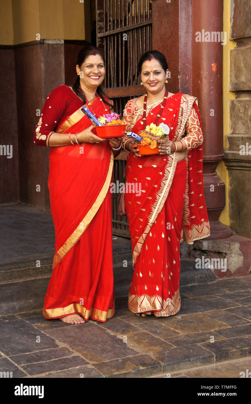 Les femmes en saris colorés de rouge et d'or hold offrandes religieuses au temple hindou de Pashupatinath, Vallée de Katmandou, Népal Banque D'Images