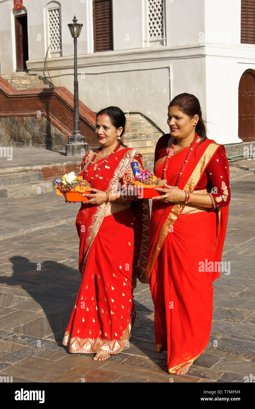 Les femmes en saris colorés de rouge et d'or hold offrandes religieuses au temple hindou de Pashupatinath, Vallée de Katmandou, Népal Banque D'Images