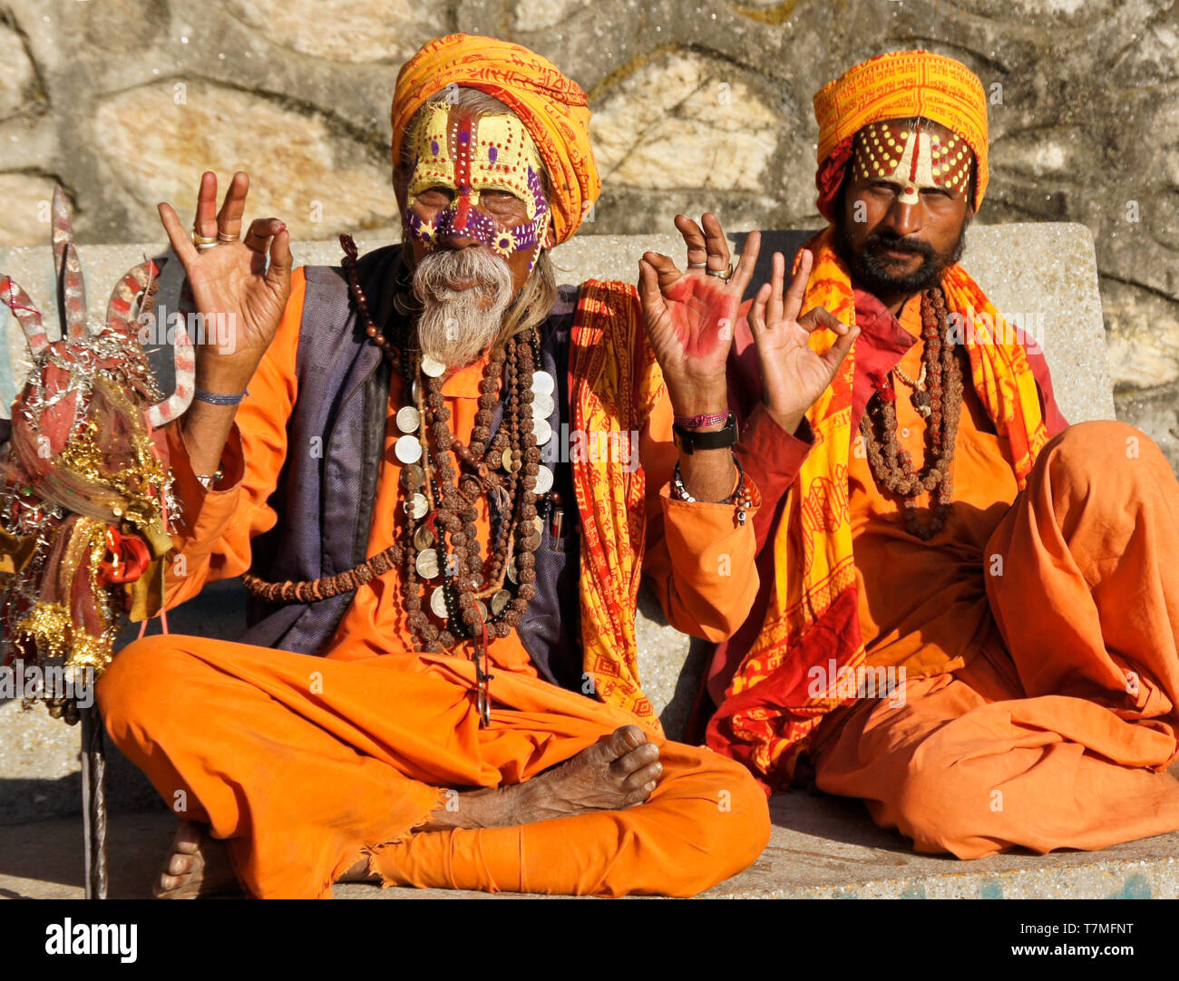 Deux sadhus (saints hommes) avec des visages peints, vêtus de robes orange, s'asseoir sur un banc au temple hindou de Pashupatinath, Vallée de Katmandou, Népal Banque D'Images