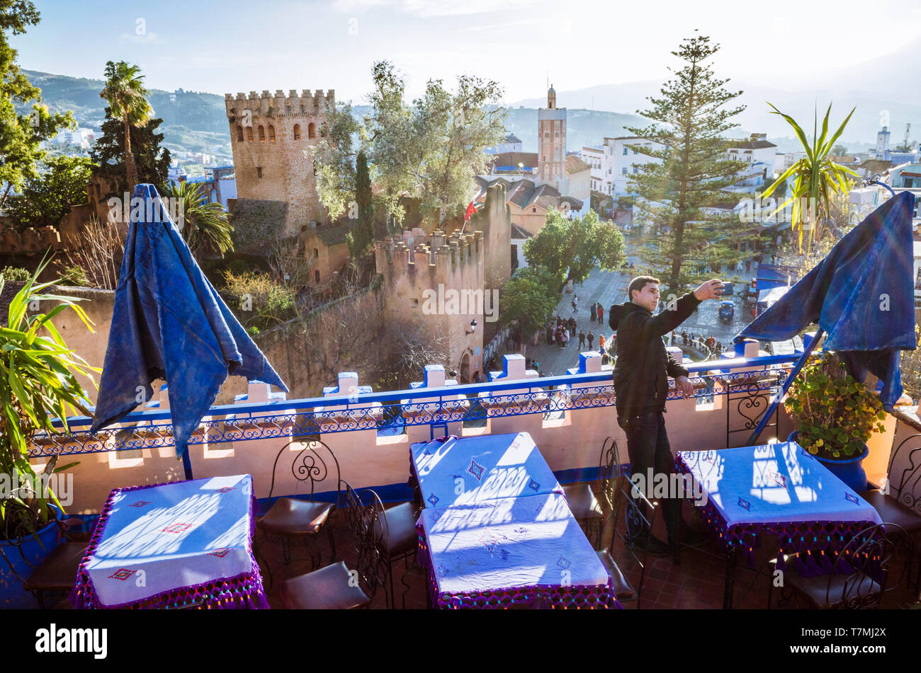 Chefchaouen, Maroc : un homme prend une à selfies le toit de l'Hôtel Aladin avec la Kasbah forteresse en arrière-plan. Banque D'Images