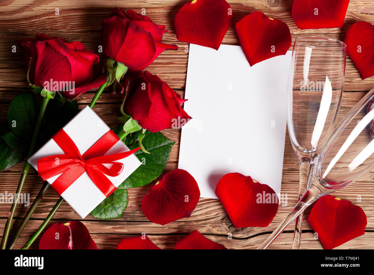 Roses rouges avec un cadeau et le verre à champagne sur fond de bois Banque D'Images