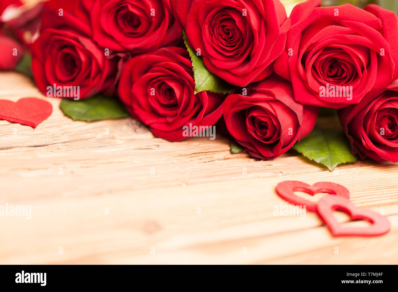 Roses rouges avec des coeurs sur table en bois Banque D'Images