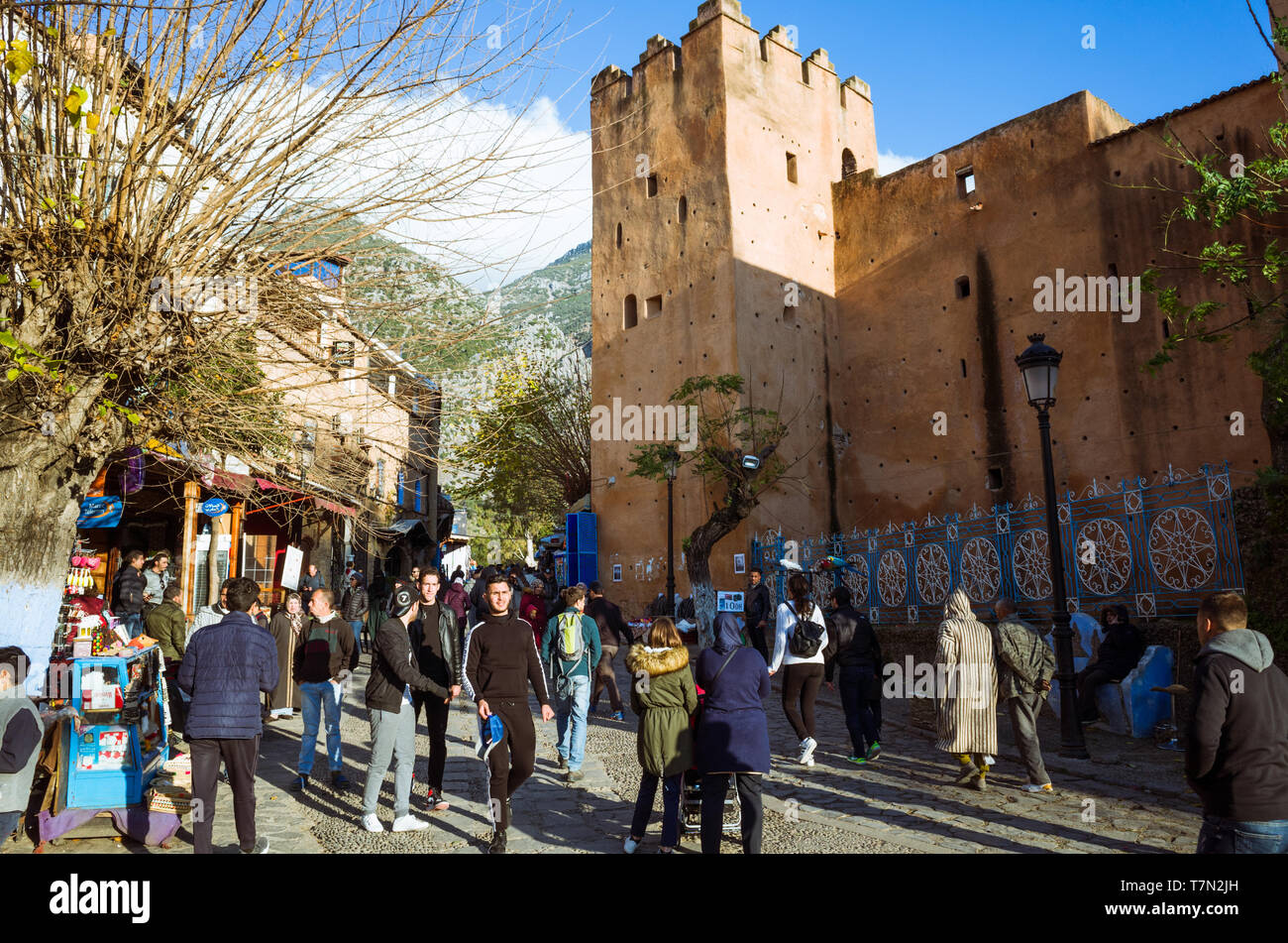 Chefchaouen, Maroc : Les gens passent devant la Kasbah forteresse à Uta el-Hammam place principale. Banque D'Images