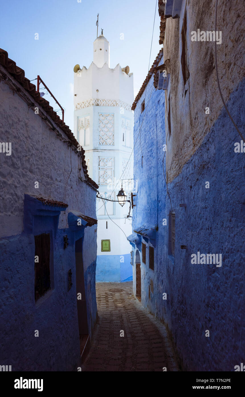 Chefchaouen, Maroc : une ruelle lavés sous le minaret d'une mosquée dans la médina, vieille ville. Banque D'Images