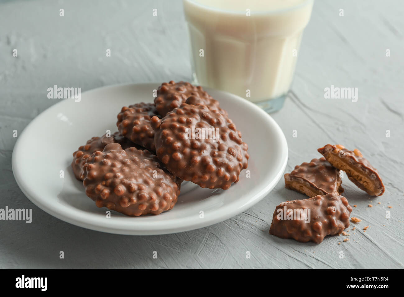 Verre de lait et la plaque de chocolat cookies sur table gris Banque D'Images