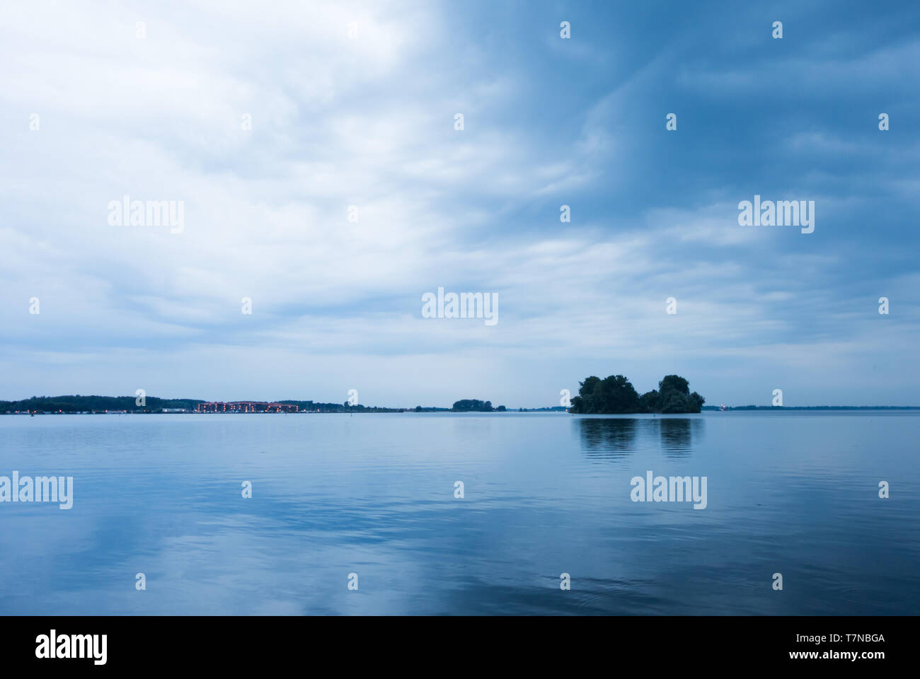 L'eau du lac encore soirée calme arbres sur l'horizon Banque D'Images