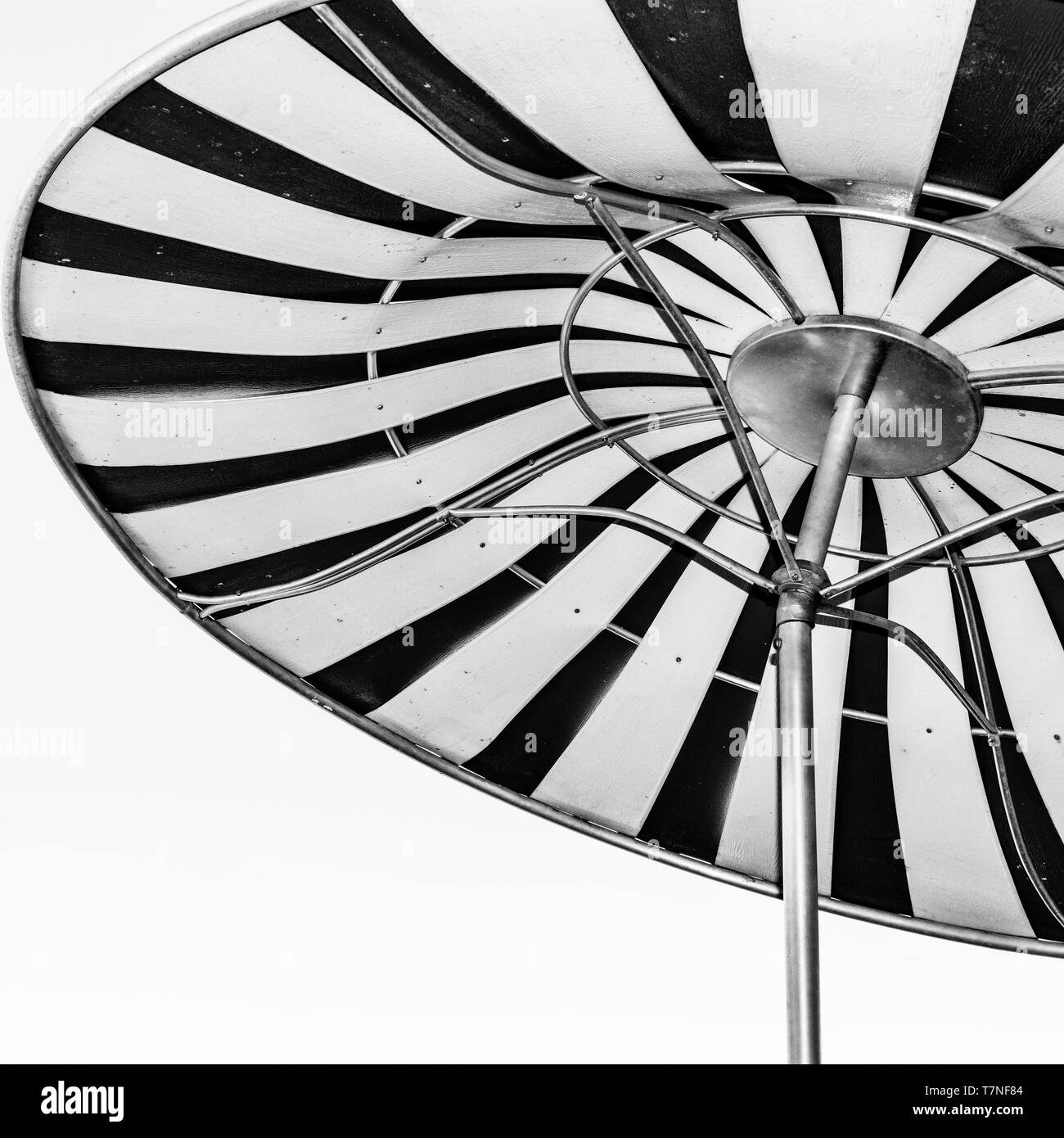 Vue vers le haut donne une image abstraite de grand, le métal et le cuir, rouge et blanc à rayures parasol à espace extérieur, en noir et blanc Banque D'Images