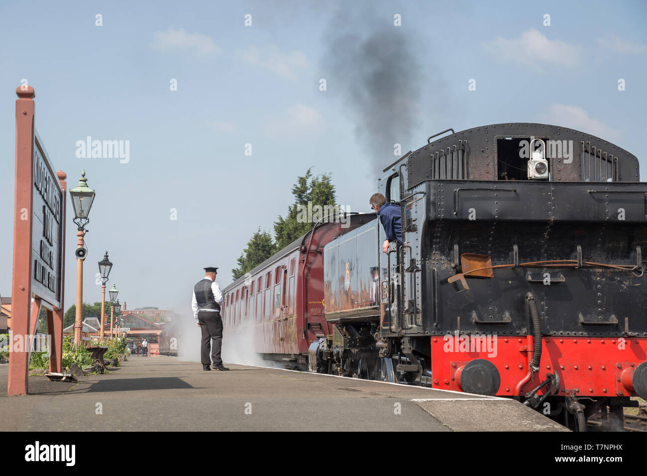 Vue arrière du vintage UK locomotive à vapeur par la plate-forme à Kidderminster SVR gare ferroviaire patrimoniale à Sunshine, conducteur de train en attente de drapeau vert. Banque D'Images