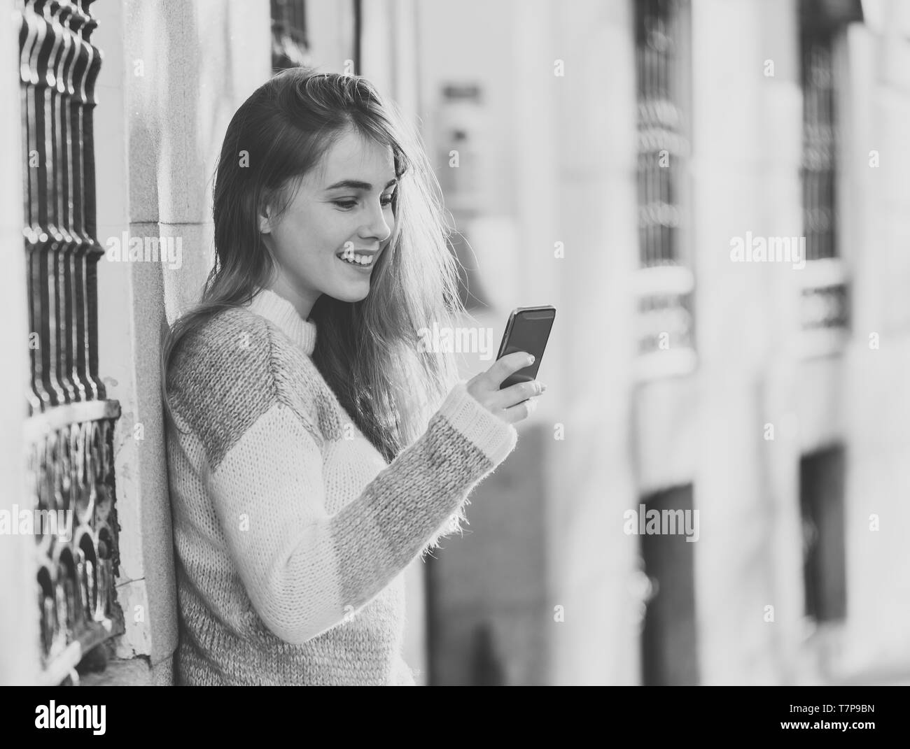 Joli happy student woman chatting online sur smart phone en utilisant des applications de médias sociaux à l'extérieur de la ville. Beautiful teenager portant des vêtements élégants se sentir Banque D'Images