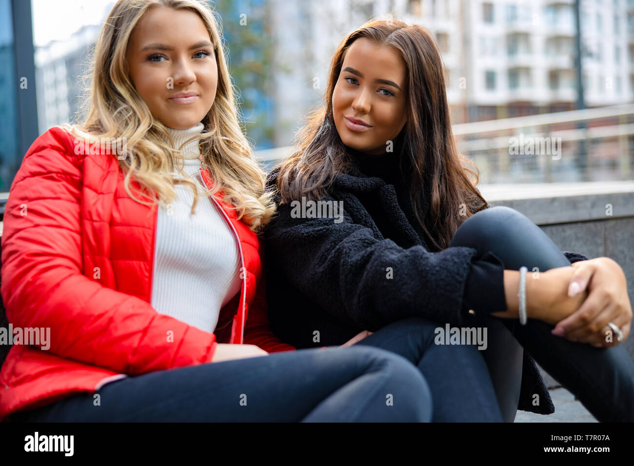 Portrait of Two Female Friends Sitting In City Banque D'Images