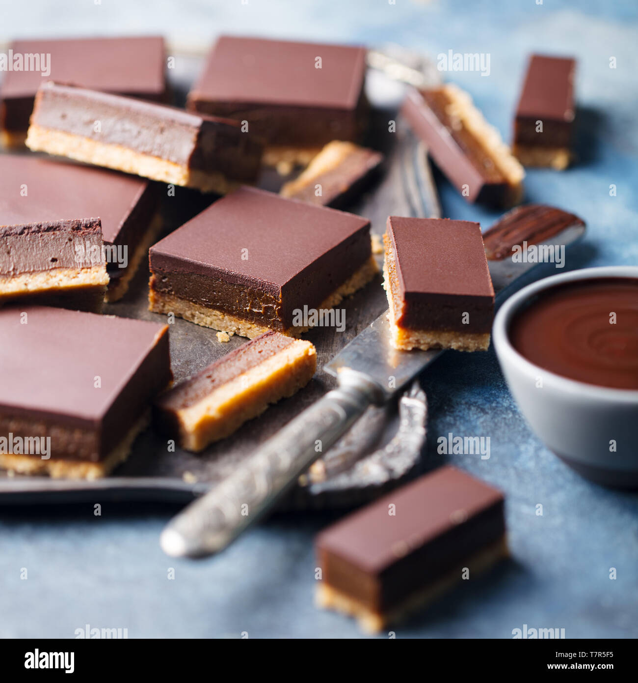 Tranches de chocolat caramel, bars, les millionnaires shortbread sur un plateau métallique fond bleu. Close up. Banque D'Images