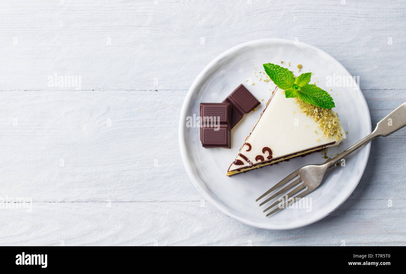 Gâteau au chocolat blanc avec feuille de menthe fraîche sur une assiette. Fond de bois. Haut vew. Copier l'espace. Banque D'Images