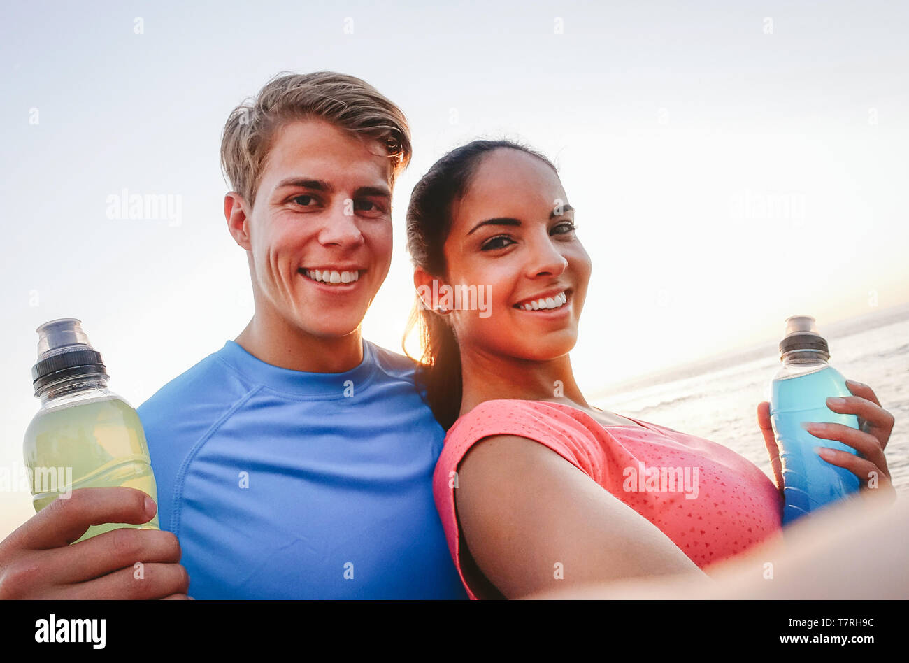 Couple sportif en tenant un téléphone mobile avec selfies au coucher du soleil - les jeunes d'avoir une pause de la formation et de boire des boissons énergétiques Banque D'Images