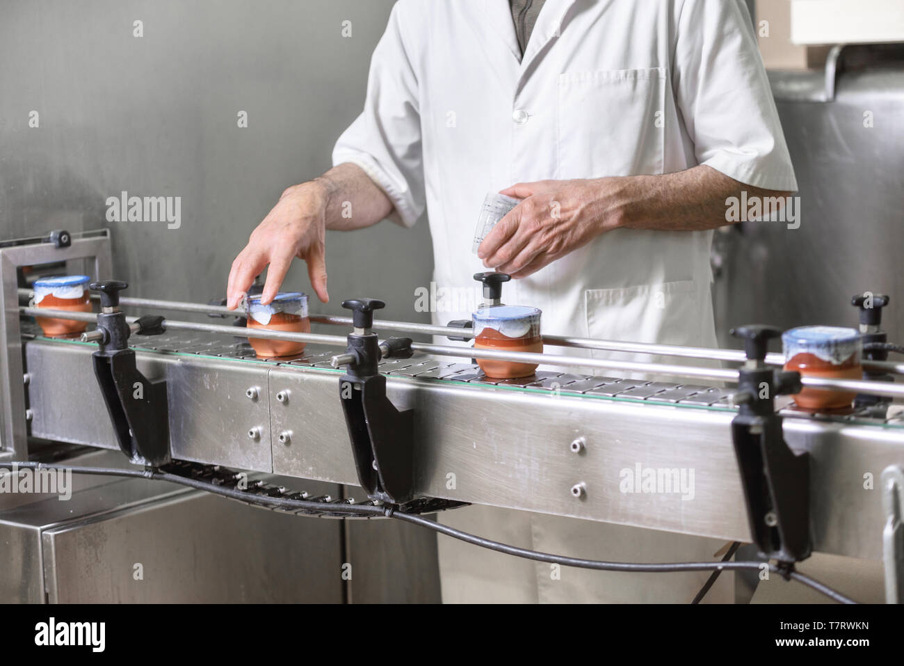 Contrôle de l'opérateur à la qualité de l'étape finale de la production. Yogurt-Filling Yaourt Premium en poterie remplie de tasses de lait moderne . Banque D'Images