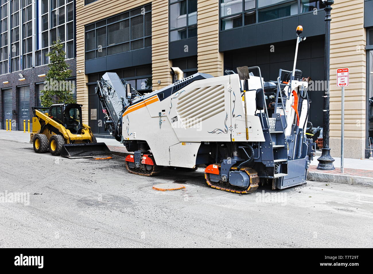 L'équipement de travail routier composé d'un petit chargeur skid steer et une route reclaimer immobilisée au bord d'un sous-chemin de construction dans une ville. Banque D'Images